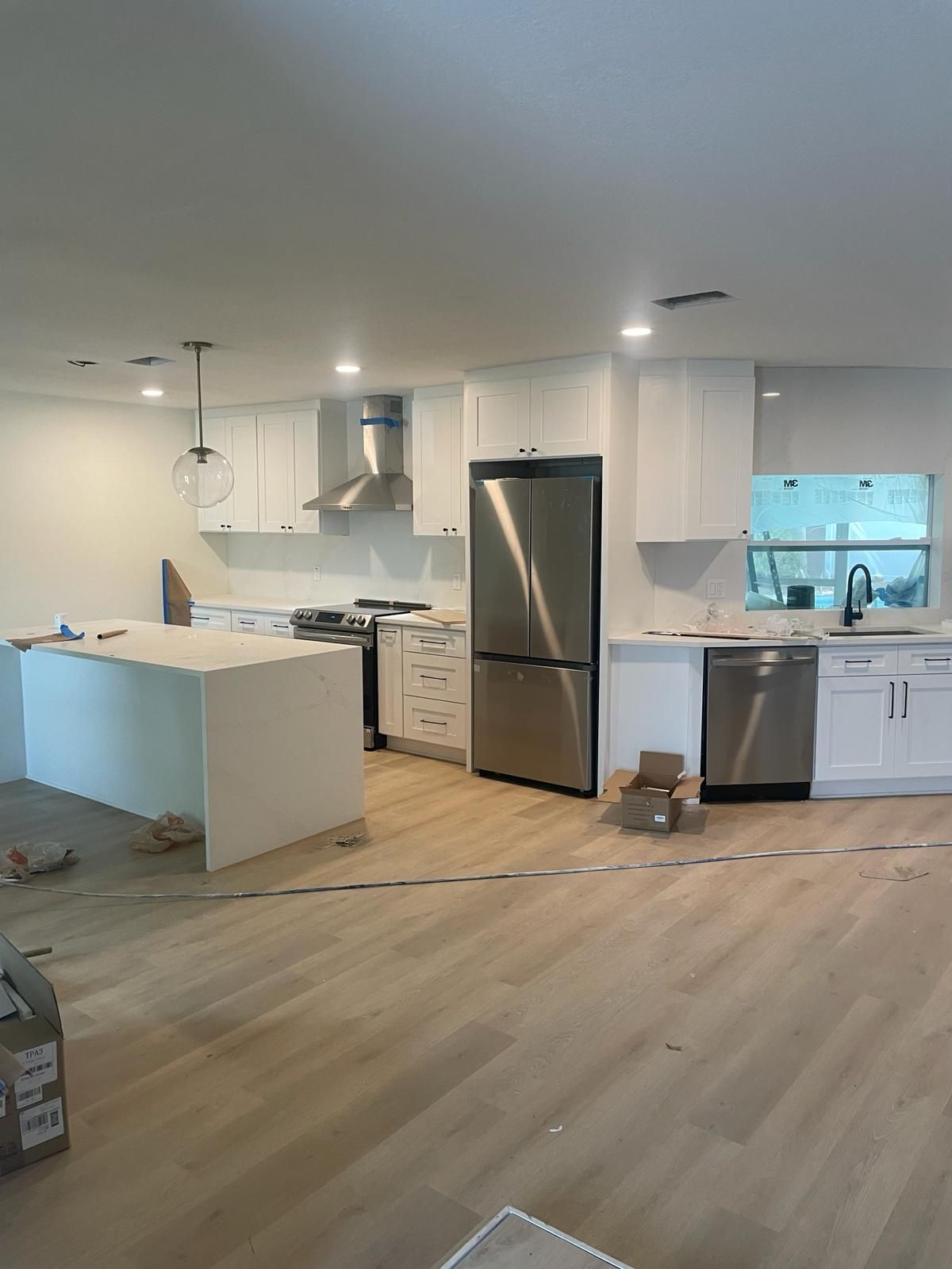 Newly renovated kitchen with white cabinets, stainless steel appliances, and a light wood floor.