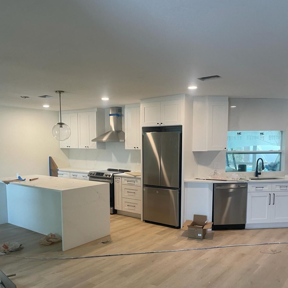 Newly renovated kitchen with white cabinets, stainless steel appliances, and wood flooring.