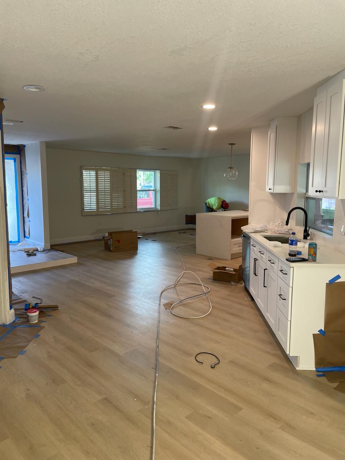 Renovated kitchen and living area, light wood floors, white cabinets, and open layout.