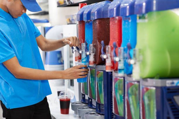 Male employee filling soda in cup from machinery.