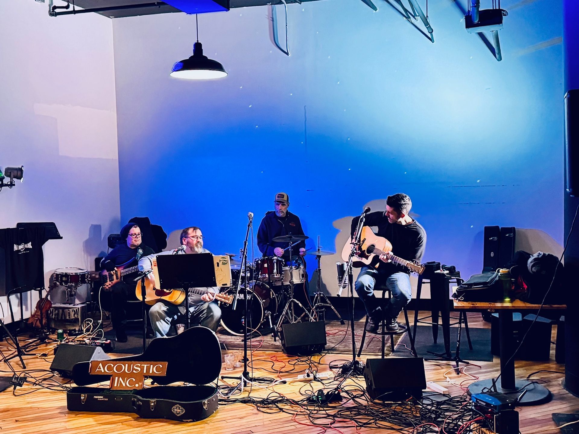 Band playing on stage with guitars and drums, bathed in blue light.