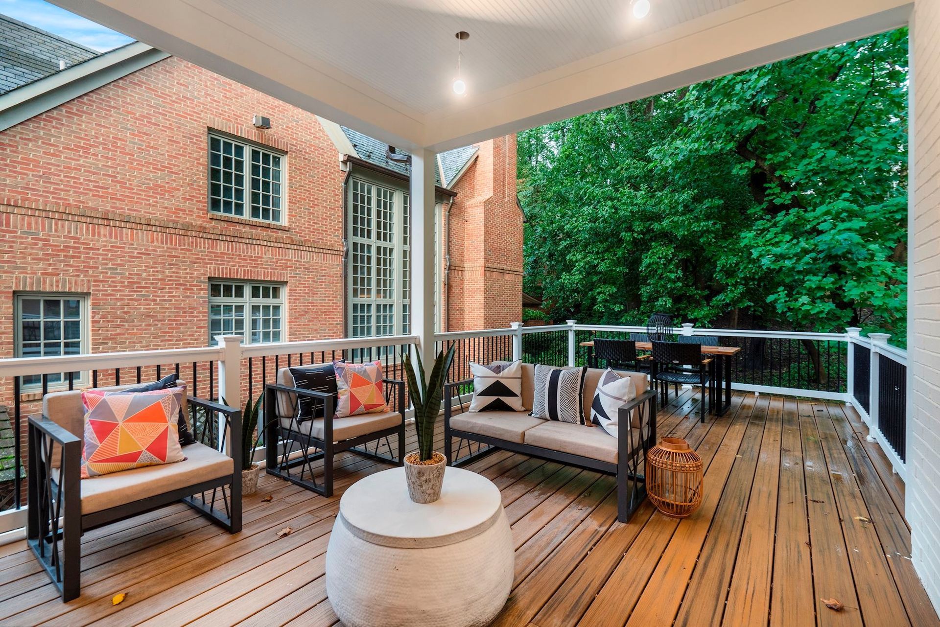 A wooden deck with a couch , chairs , and a table.