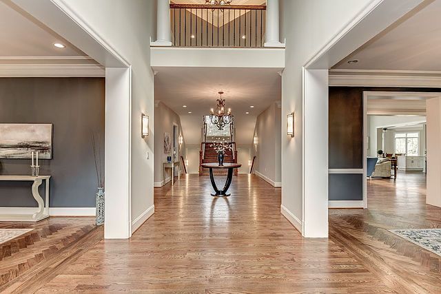 A hallway in a house with hardwood floors and a table in the middle.