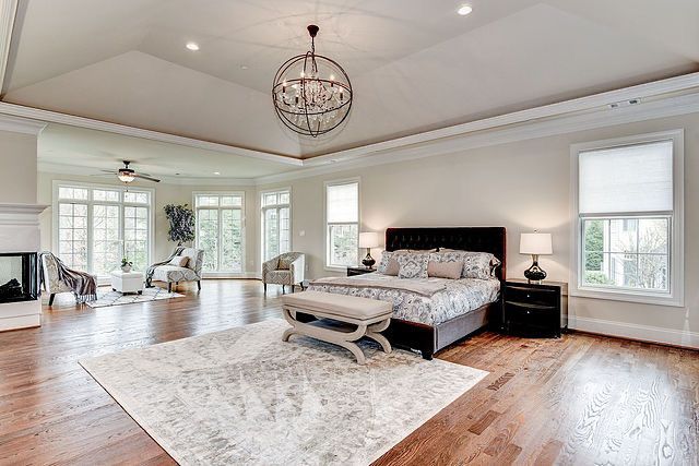 A large bedroom with hardwood floors and a large bed.