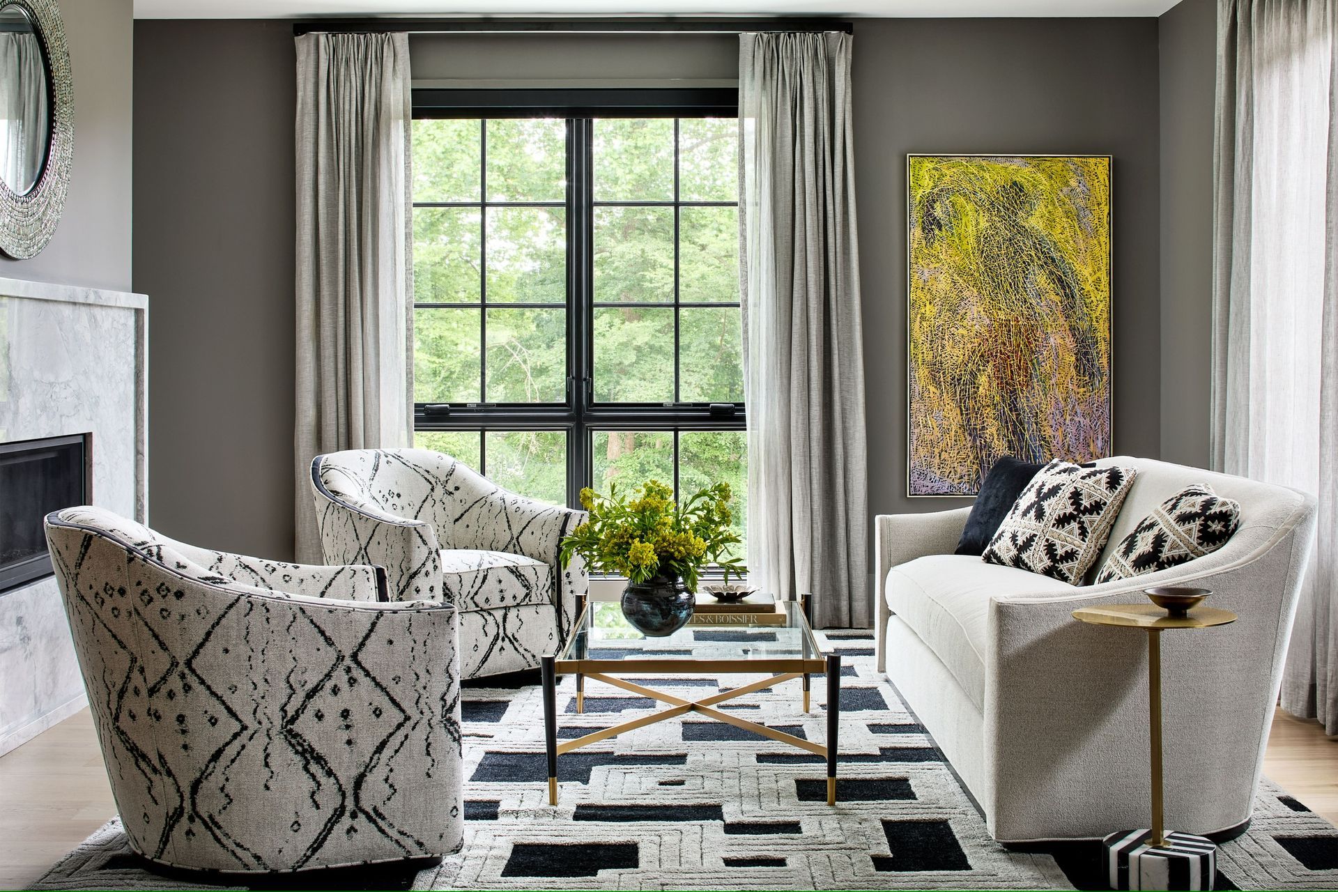 A living room with a couch , two chairs , a coffee table and a fireplace.