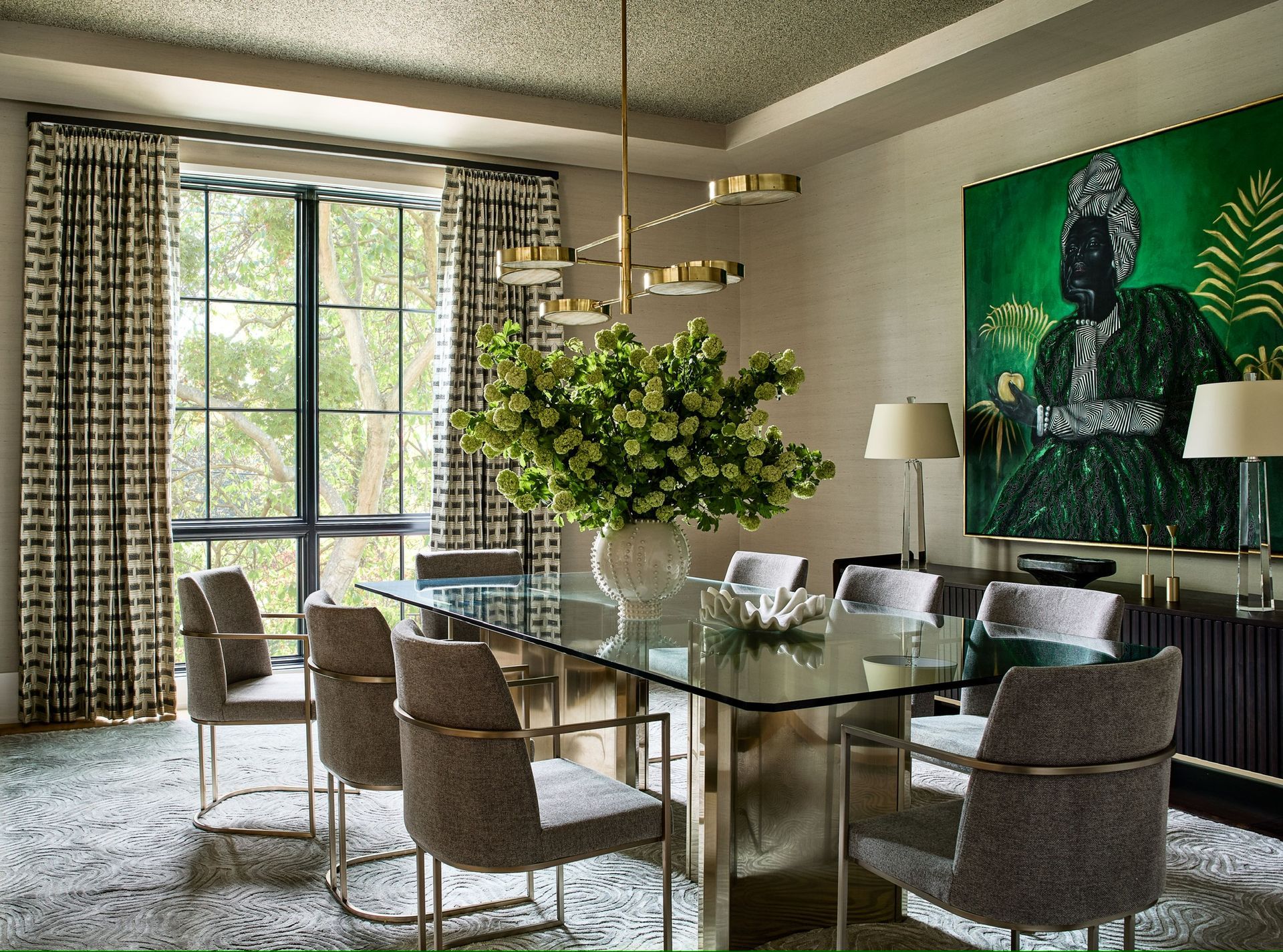 A dining room with a glass table and chairs and a painting on the wall.