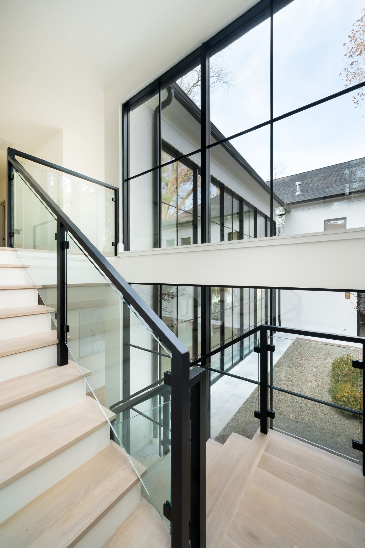 A staircase with a glass railing leading up to the second floor of a house.