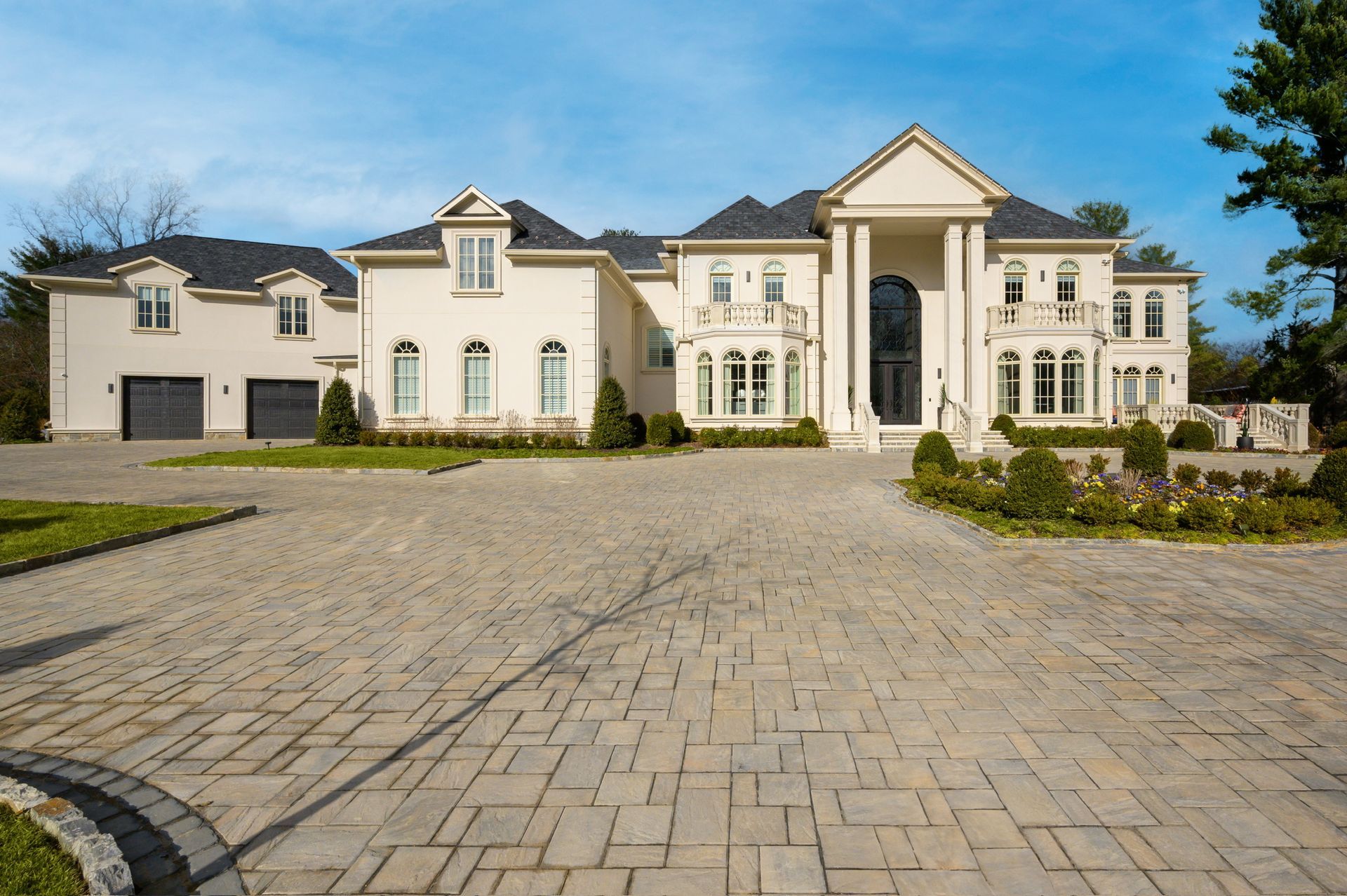 A large white house with a brick driveway in front of it