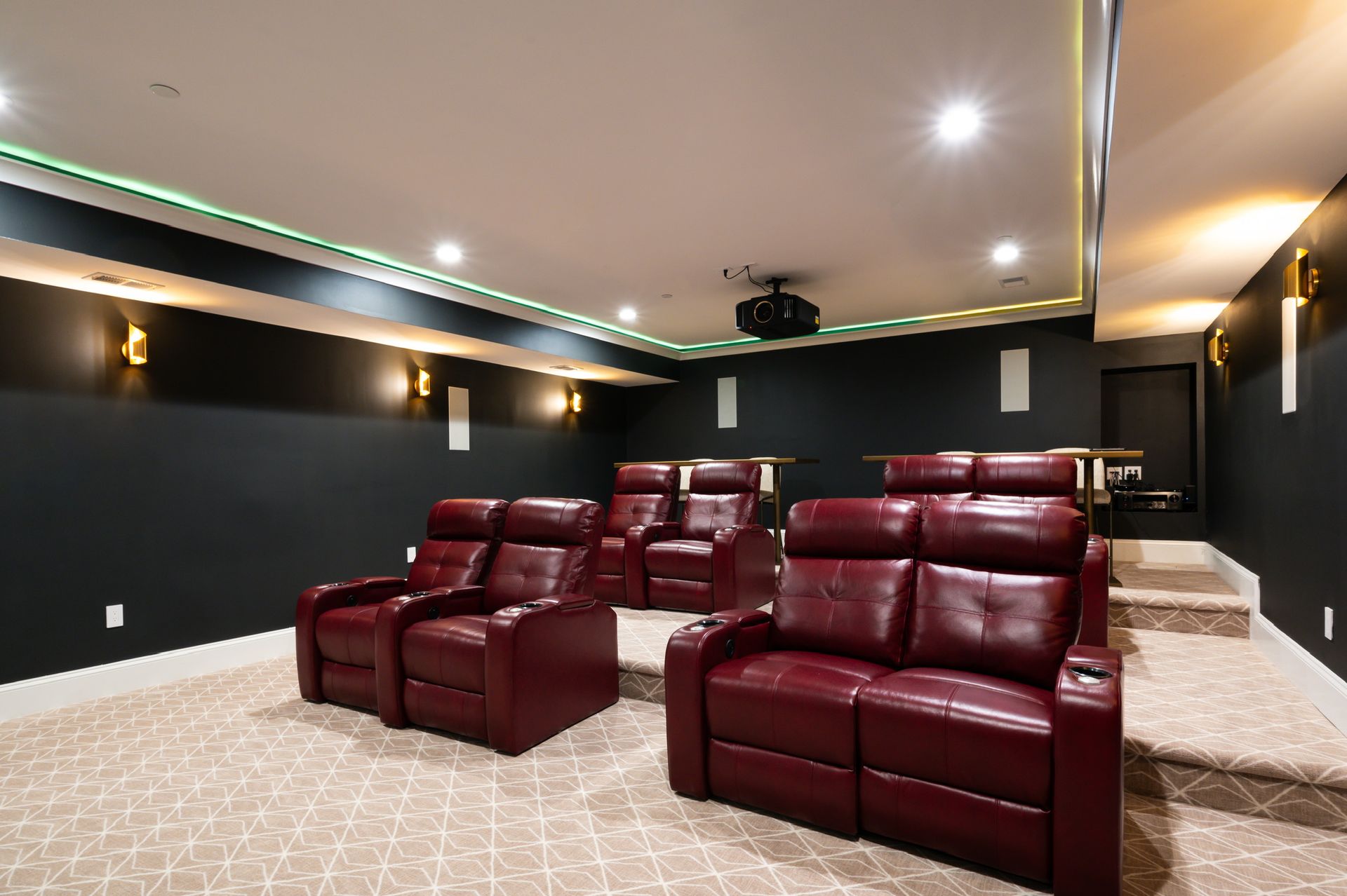 A home theater with red leather chairs and a projector.