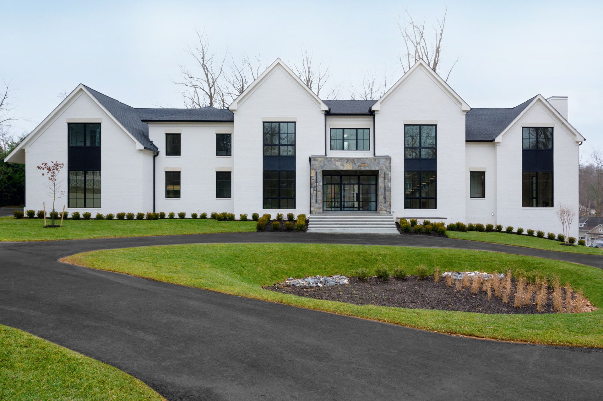 A large white house with black windows and a black driveway