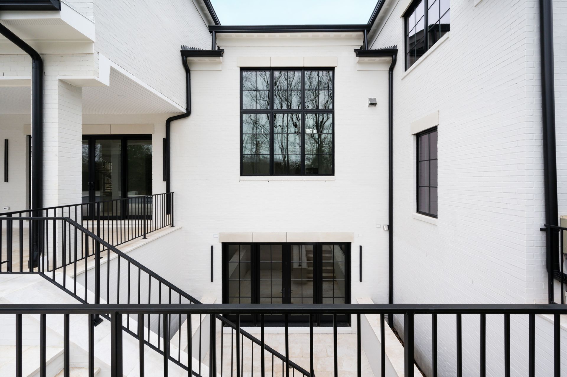 A white house with a black railing and stairs leading up to it.