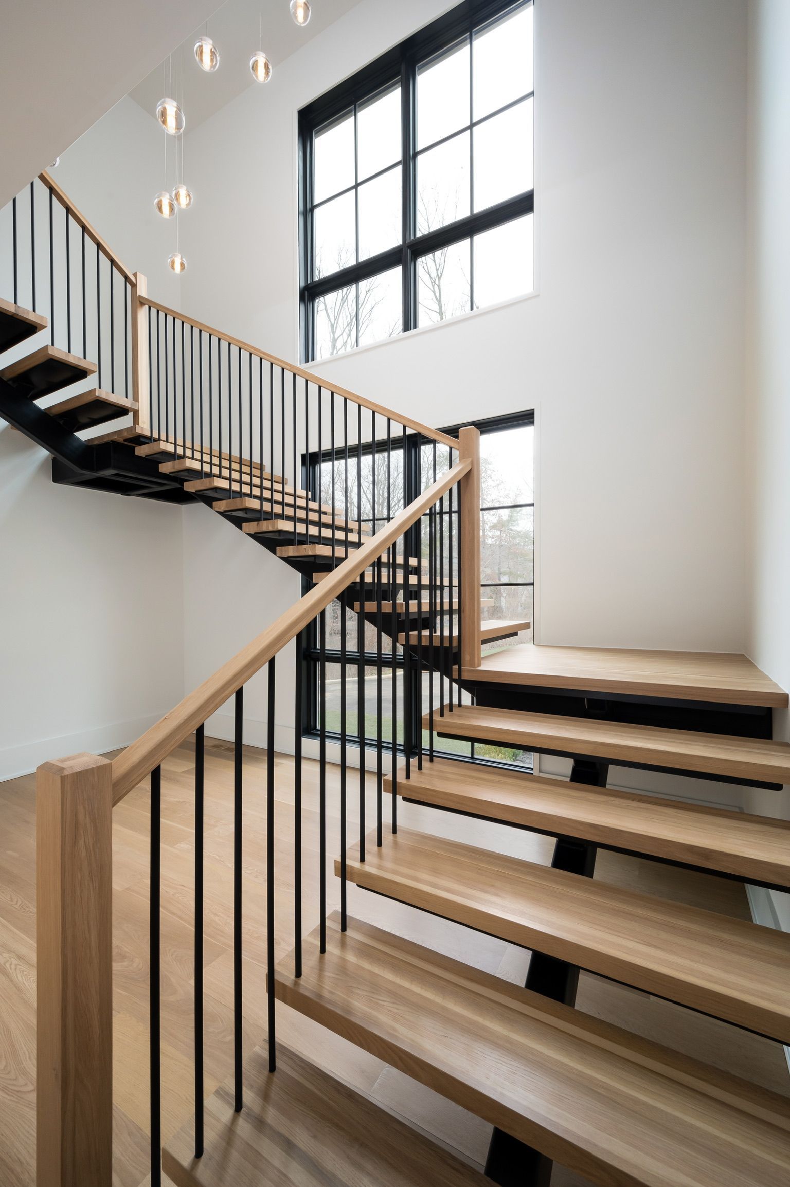 A modern staircase with wooden steps and a metal railing in a house.