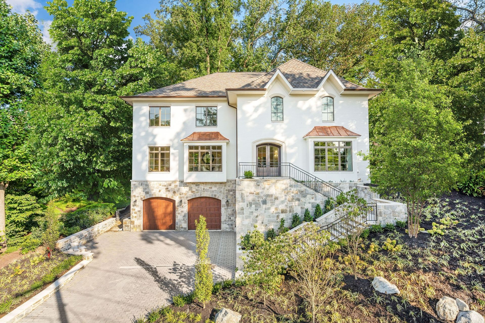 A large white house is sitting on top of a hill surrounded by trees.
