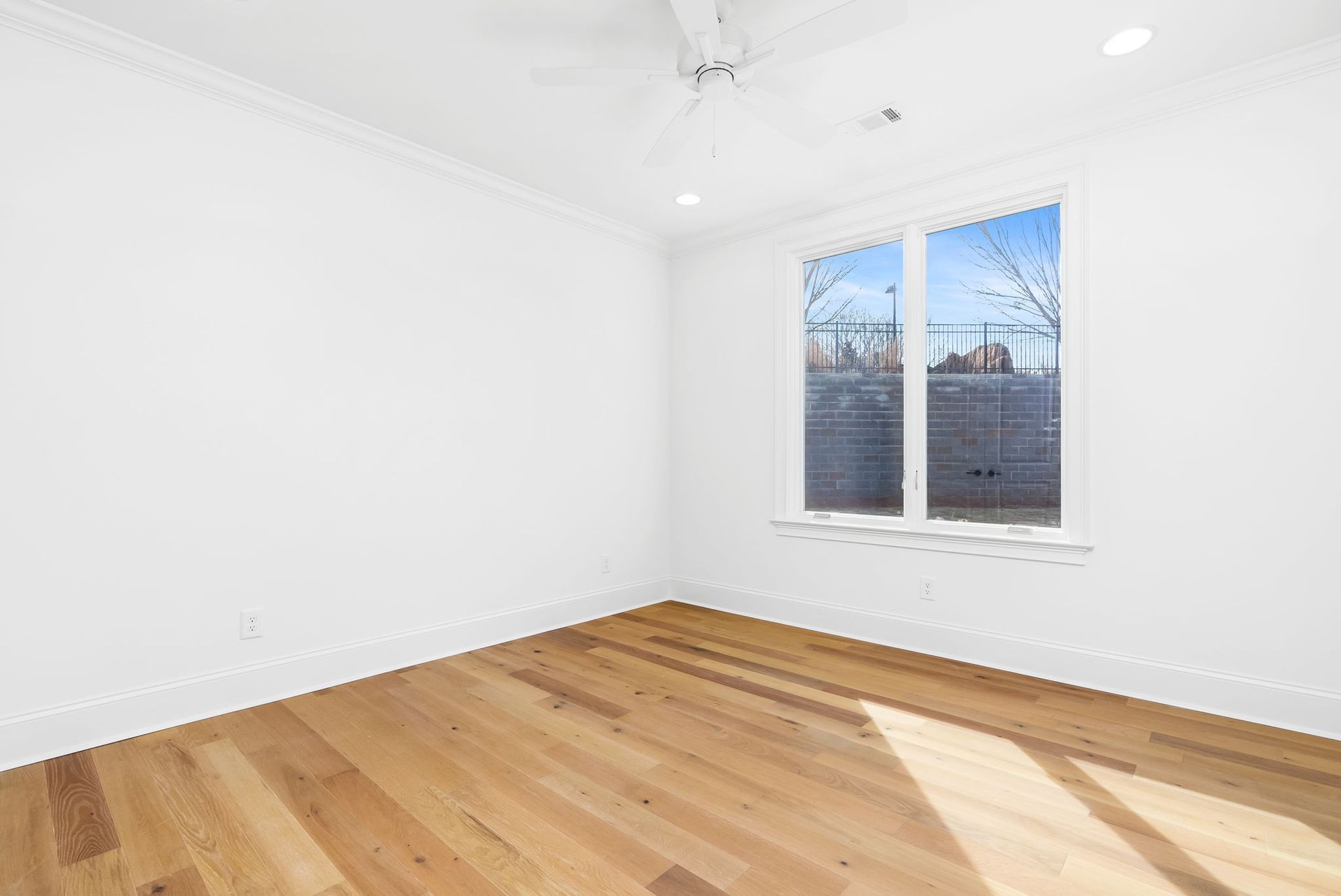 An empty room with hardwood floors and two windows.