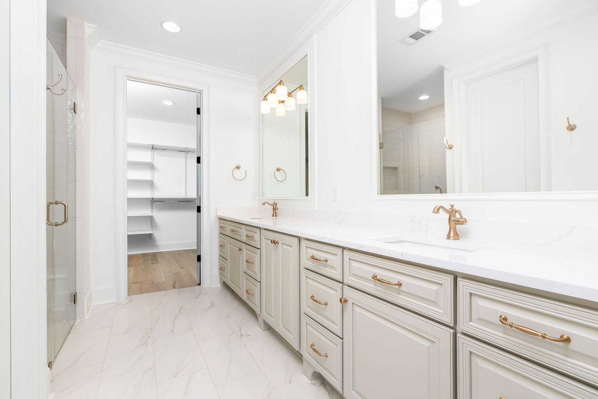 A bathroom with two sinks , two mirrors , and a walk in closet.