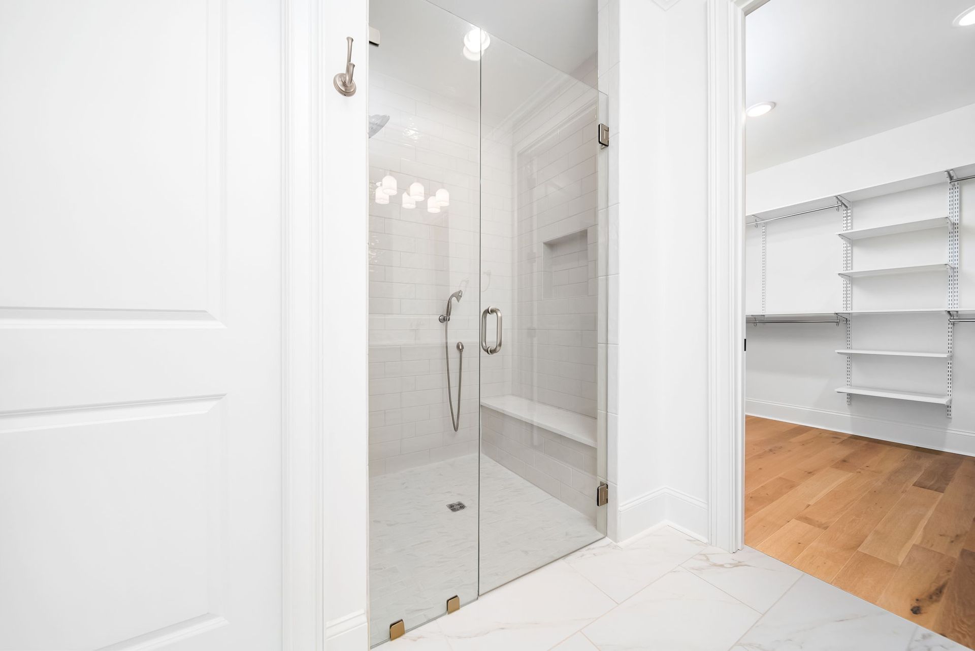 A bathroom with a walk in shower and a glass door.