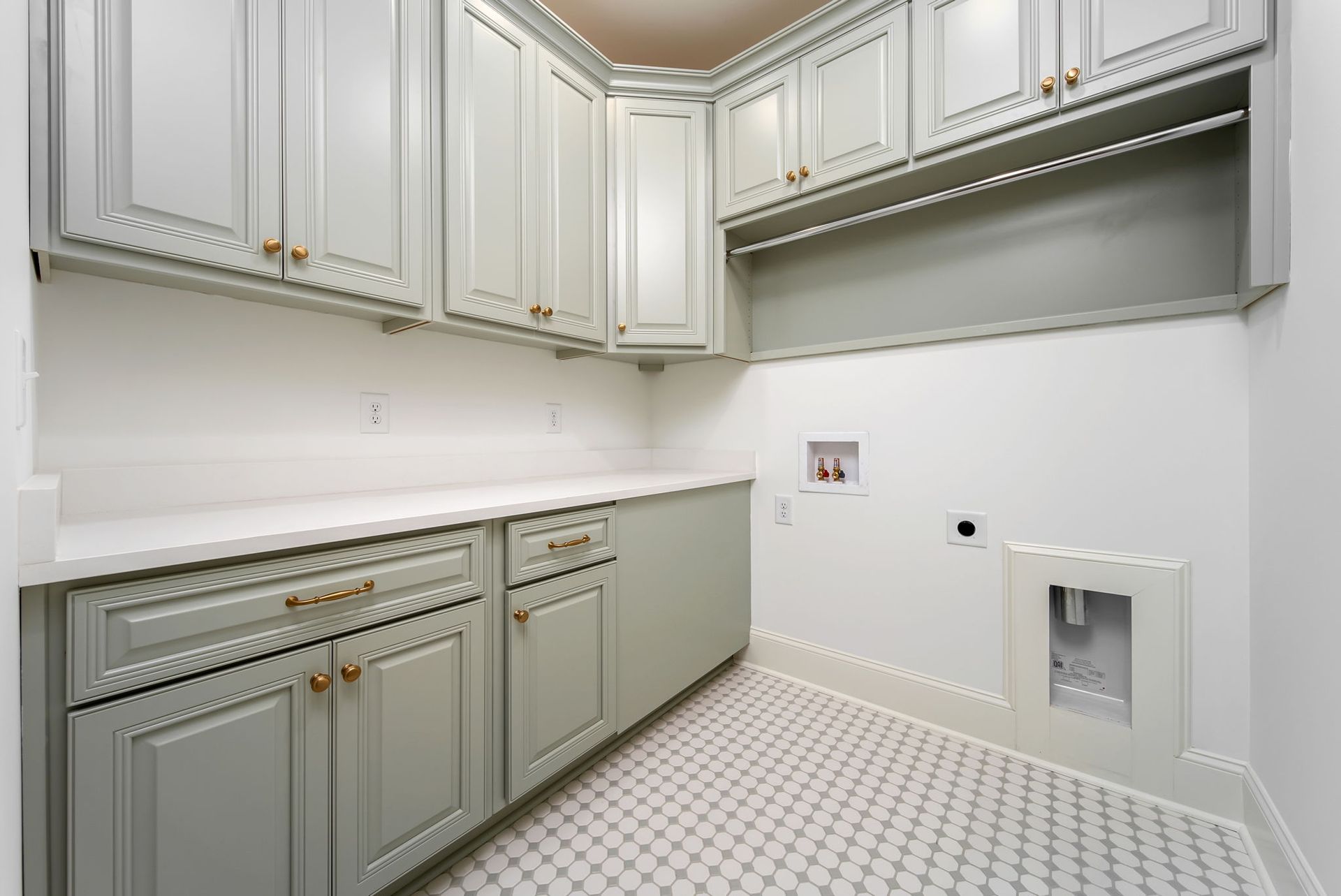 A laundry room with white cabinets and a white tile floor.