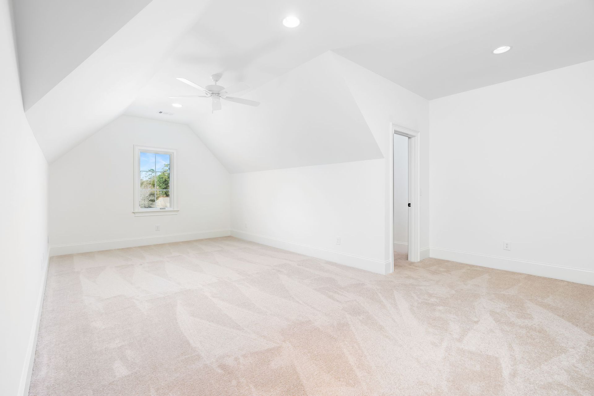 An empty bedroom with a ceiling fan and a window.