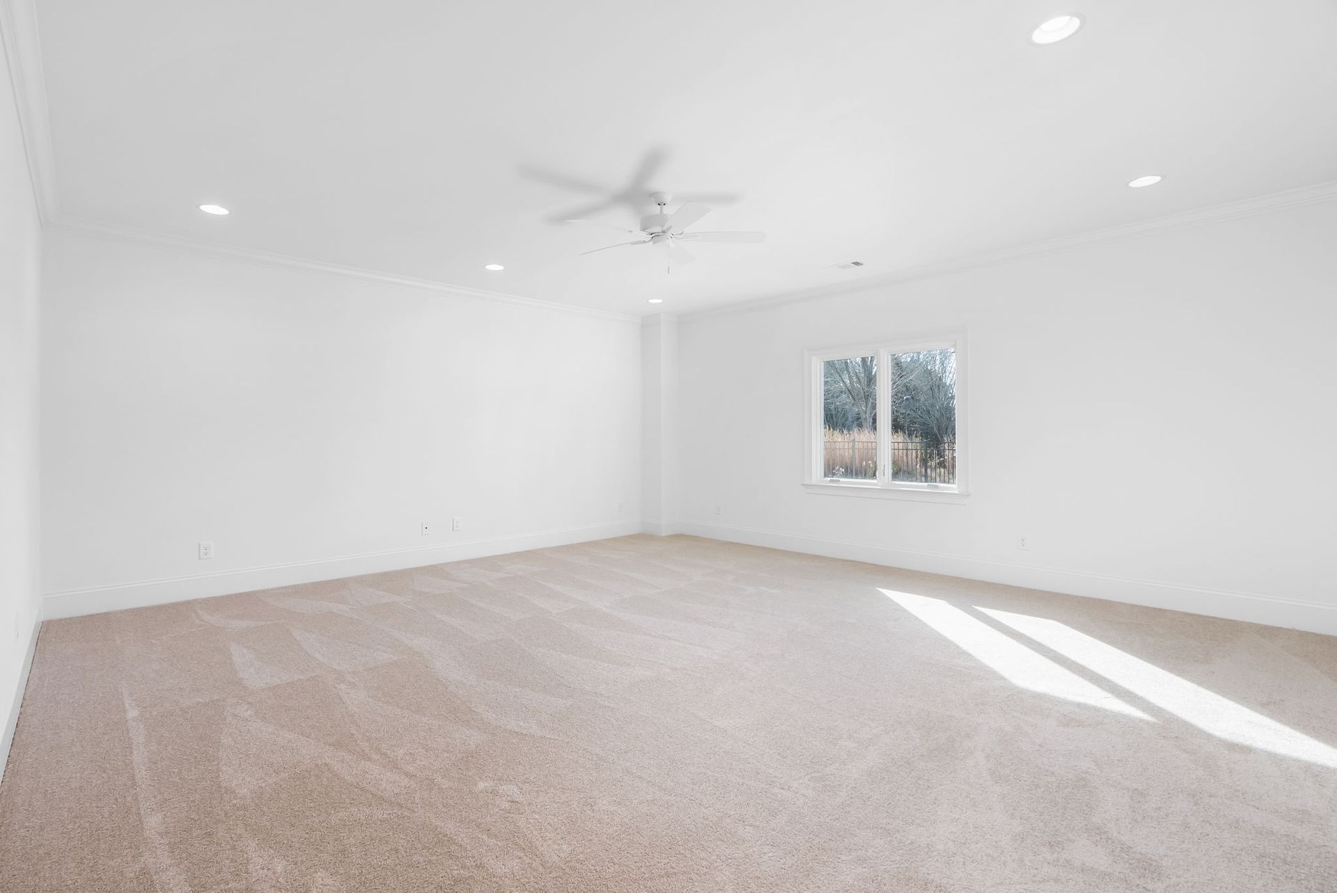 An empty bedroom with a ceiling fan and a window.