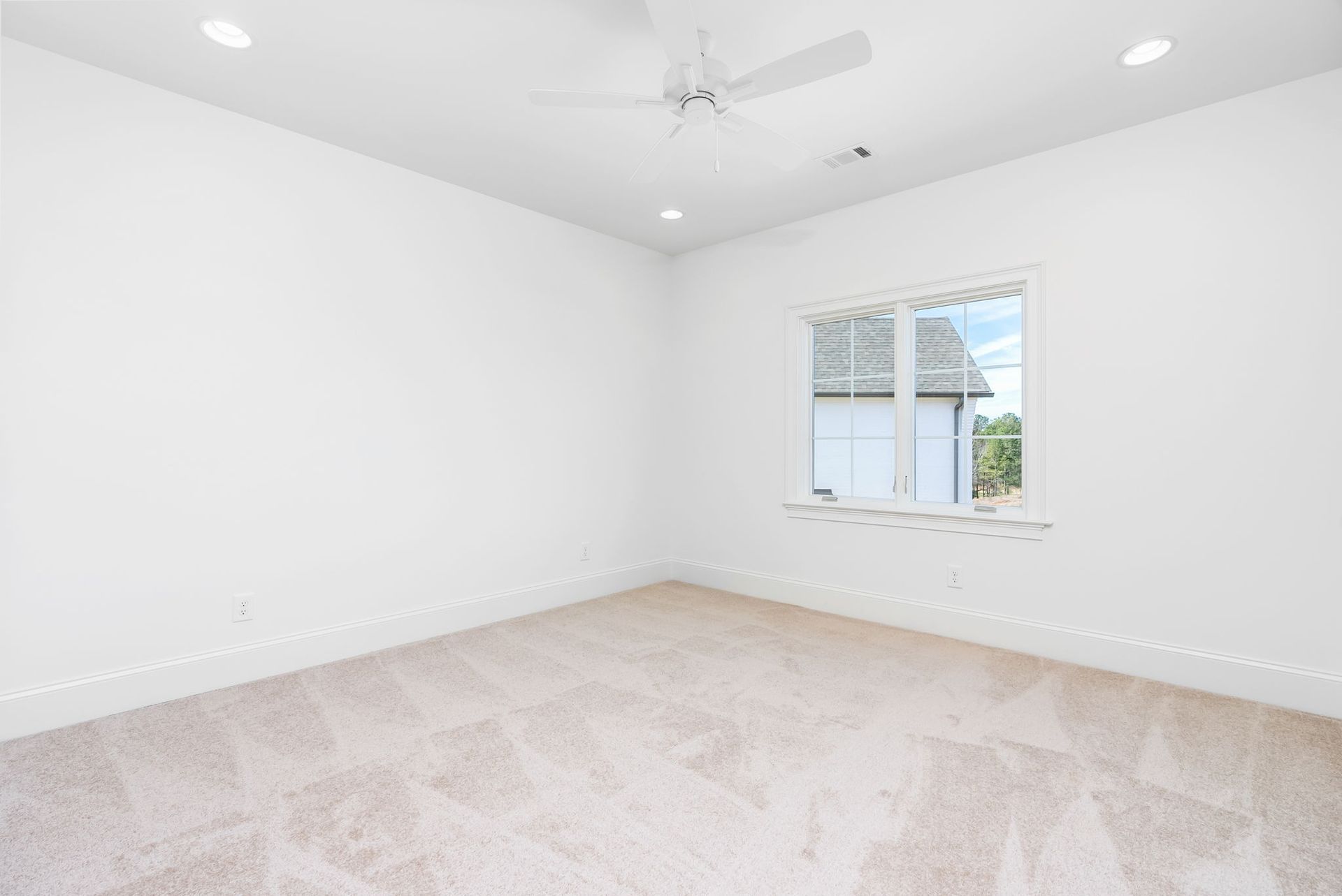 An empty bedroom with a ceiling fan and a window.