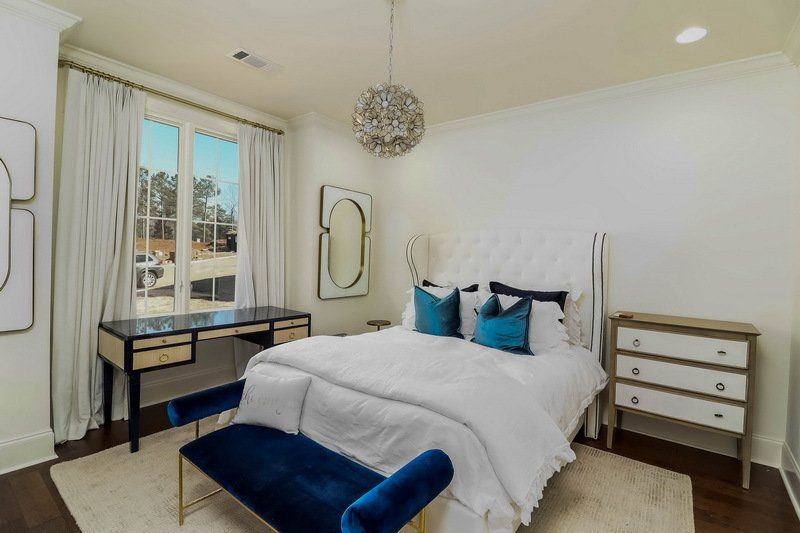 A bedroom with a bed , dresser , desk and blue bench.