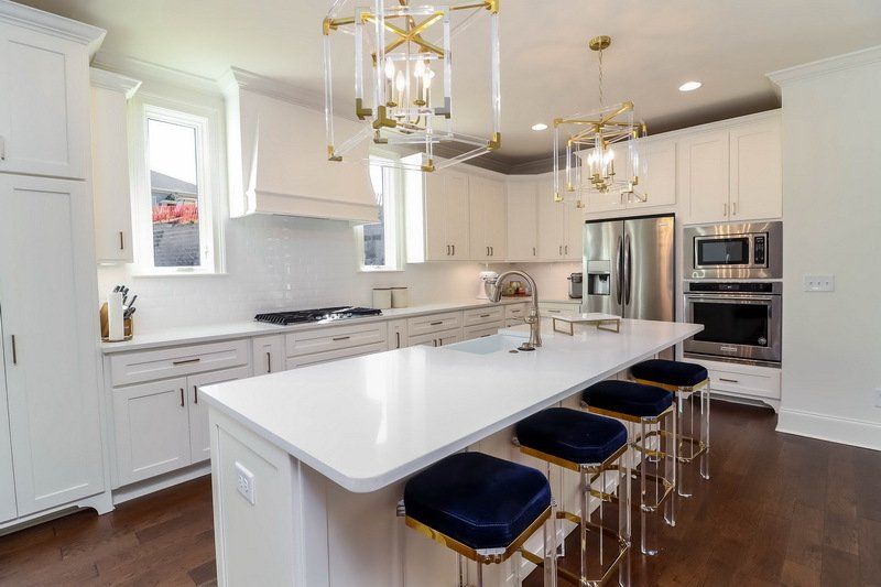 A kitchen with white cabinets , stainless steel appliances , and a large island.