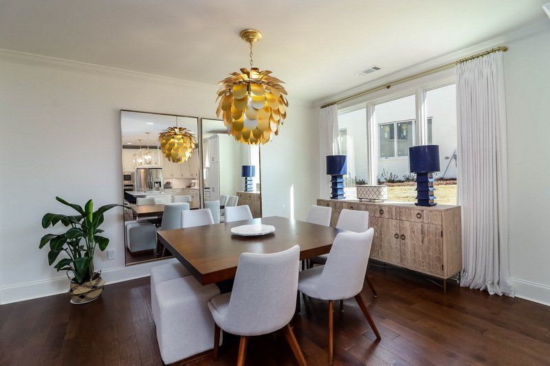 A dining room with a table and chairs and a large mirror.