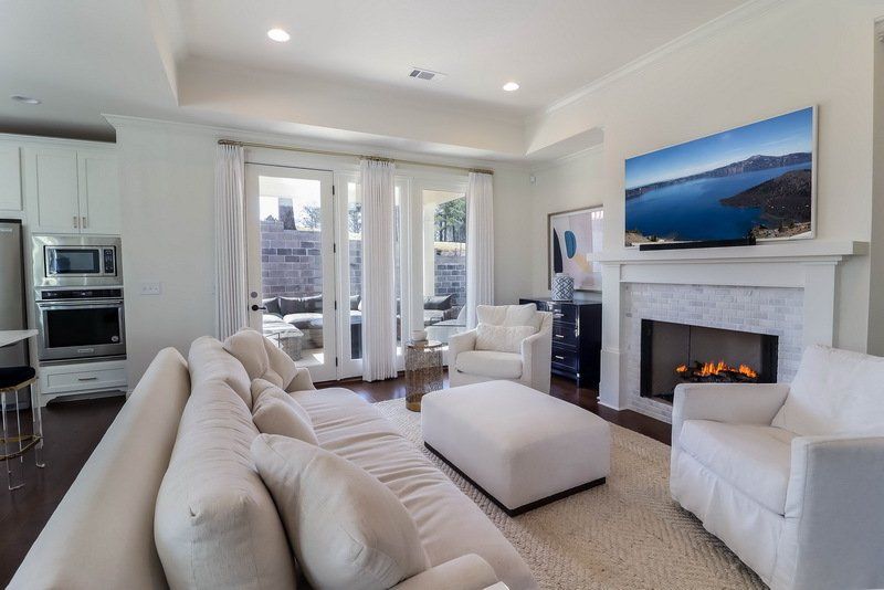 A living room with a couch , chairs , ottoman and fireplace.
