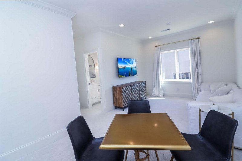 A living room with a table and chairs and a flat screen tv on the wall.