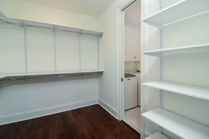 An empty walk in closet with shelves and a washer and dryer.