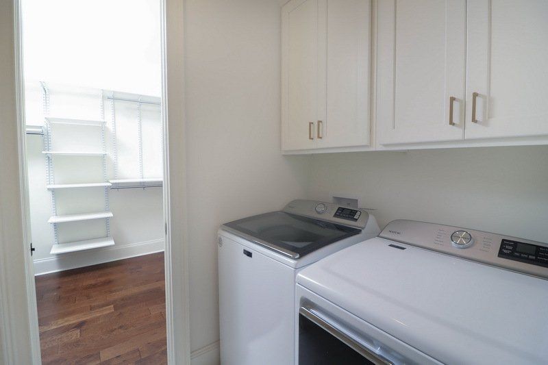 A laundry room with a washer and dryer and white cabinets.