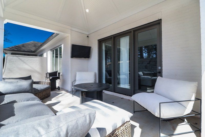 A patio with a couch , chairs , table and television.