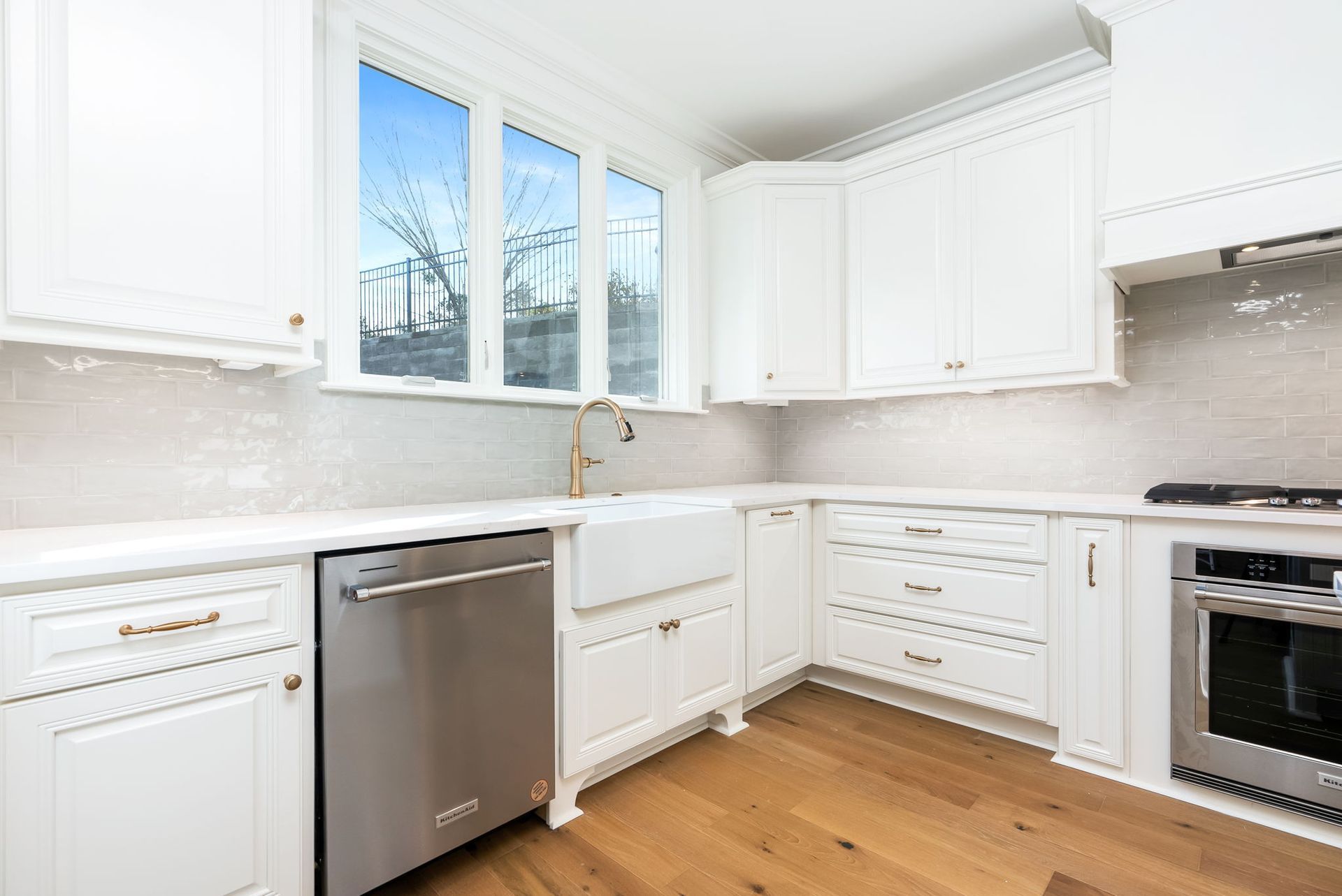 A kitchen with white cabinets , stainless steel appliances , and hardwood floors.