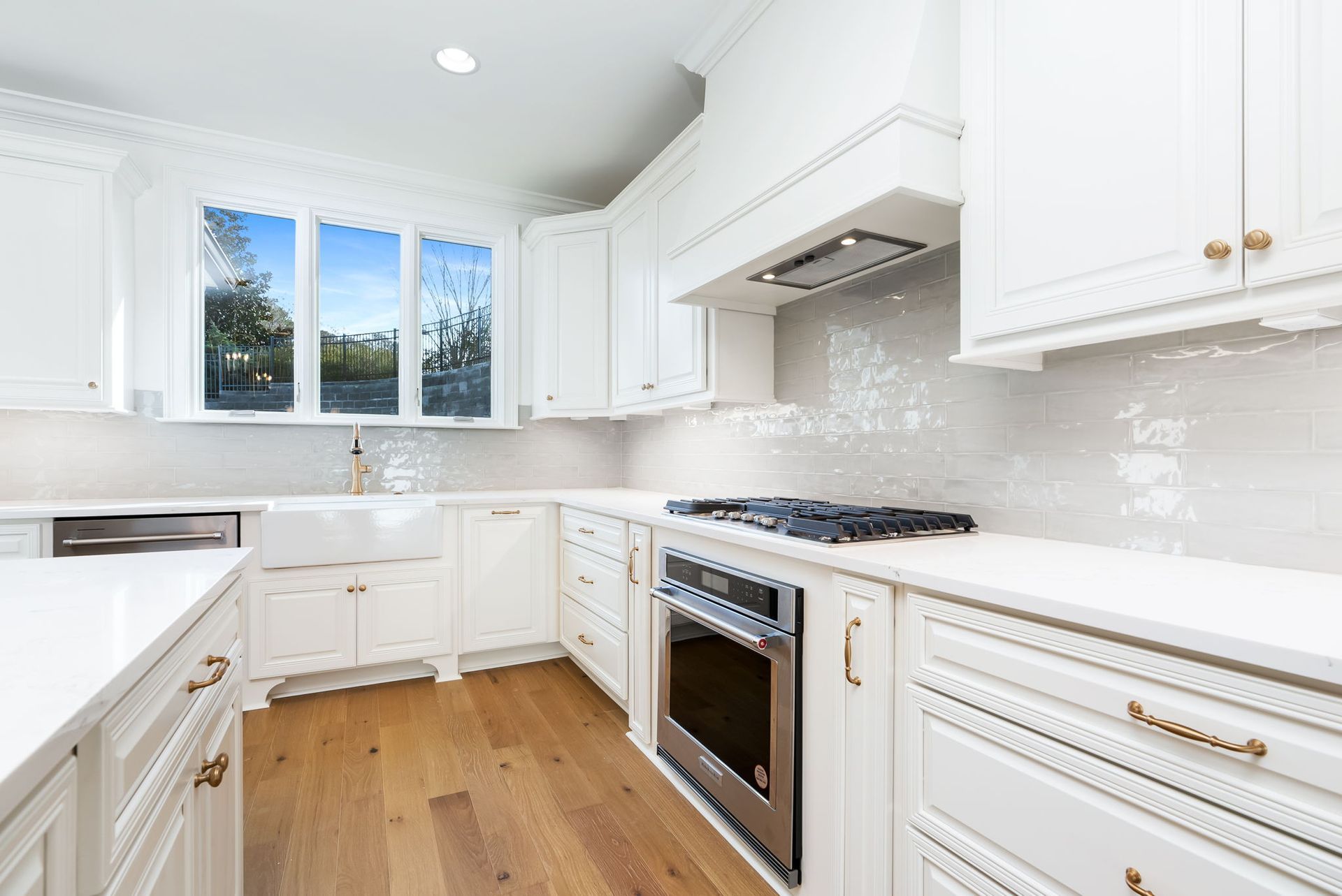 A kitchen with white cabinets , stainless steel appliances , hardwood floors and a sink.