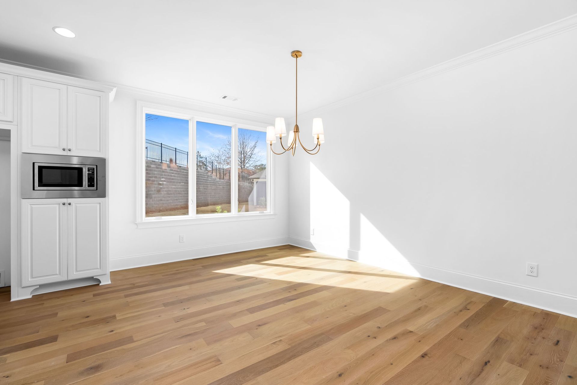 An empty living room with hardwood floors and white cabinets.
