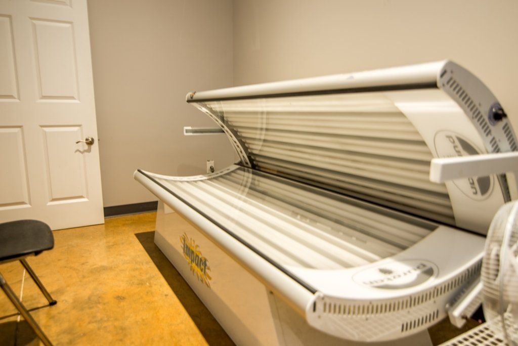 A tanning bed is sitting in a room next to a chair.