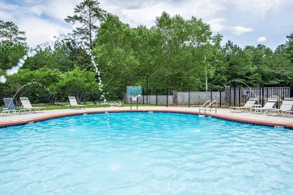 A large swimming pool surrounded by chairs and trees