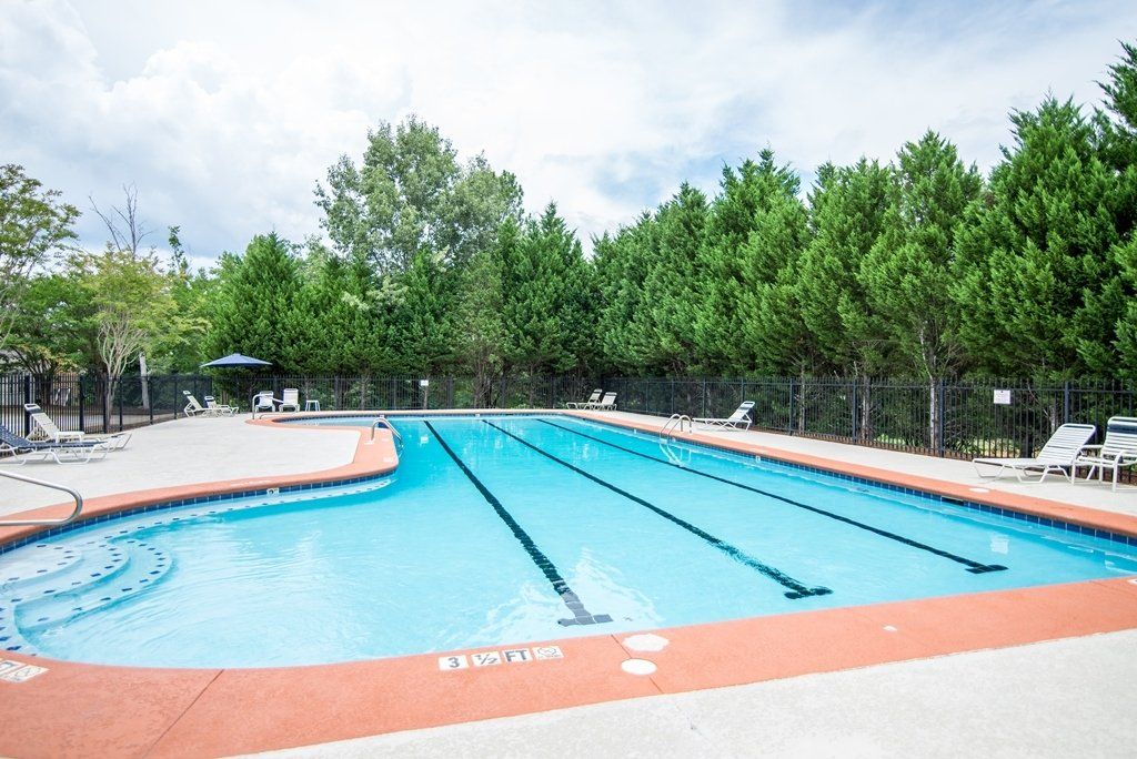 A large swimming pool surrounded by trees and chairs.