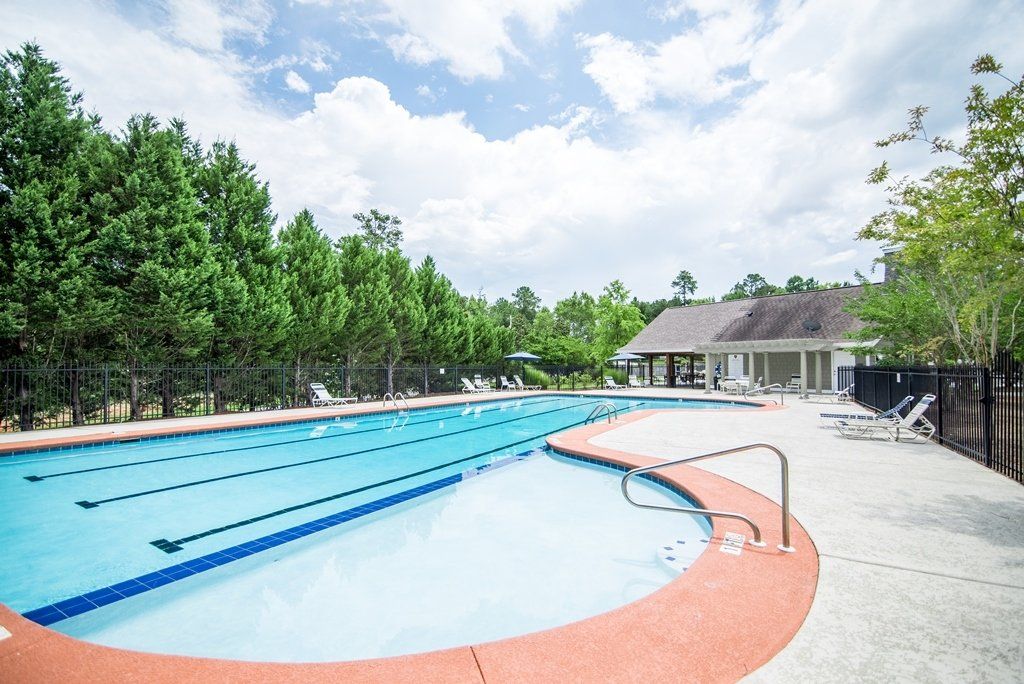 A large swimming pool surrounded by trees and a building.