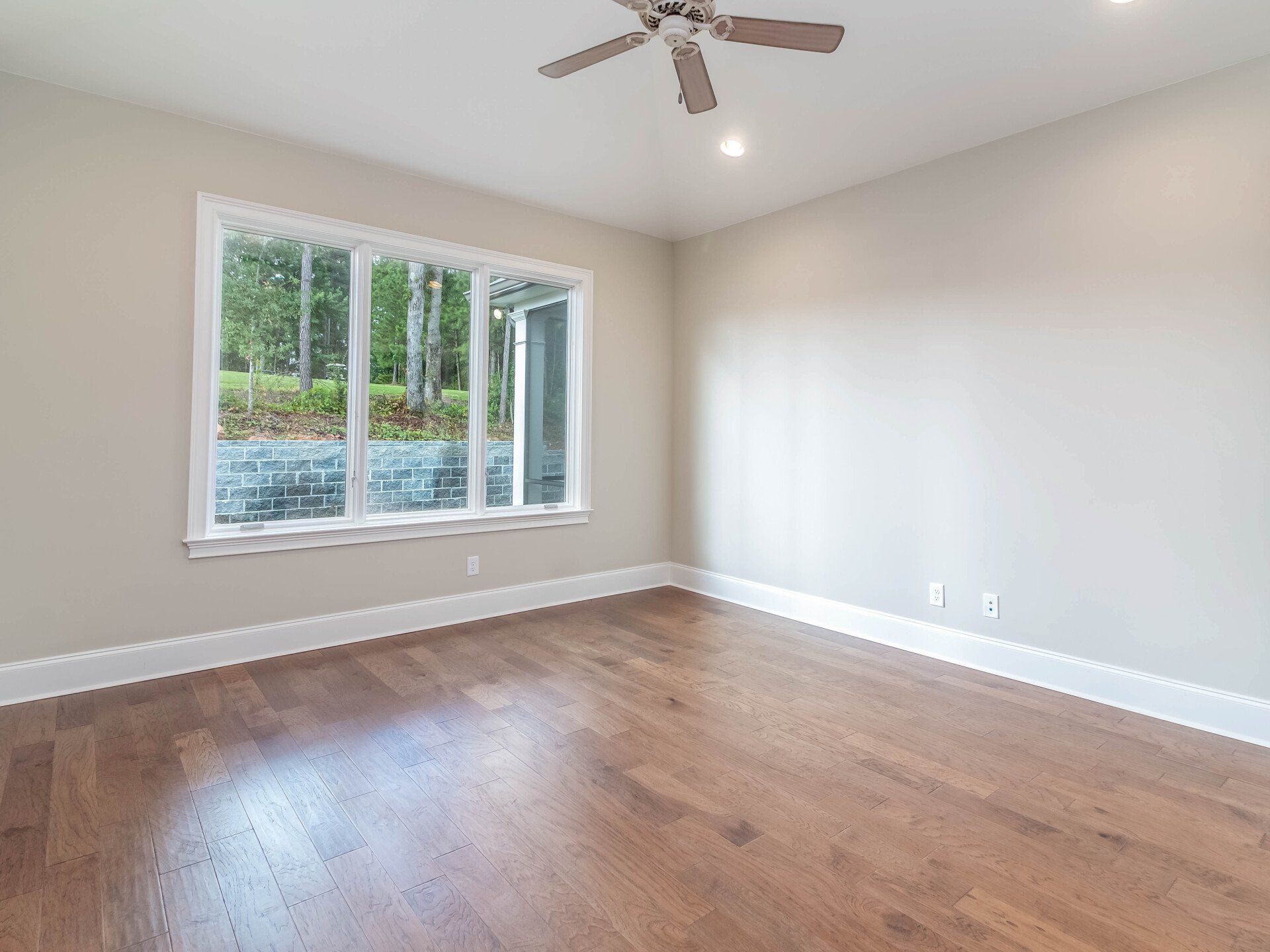 An empty room with hardwood floors and a ceiling fan.