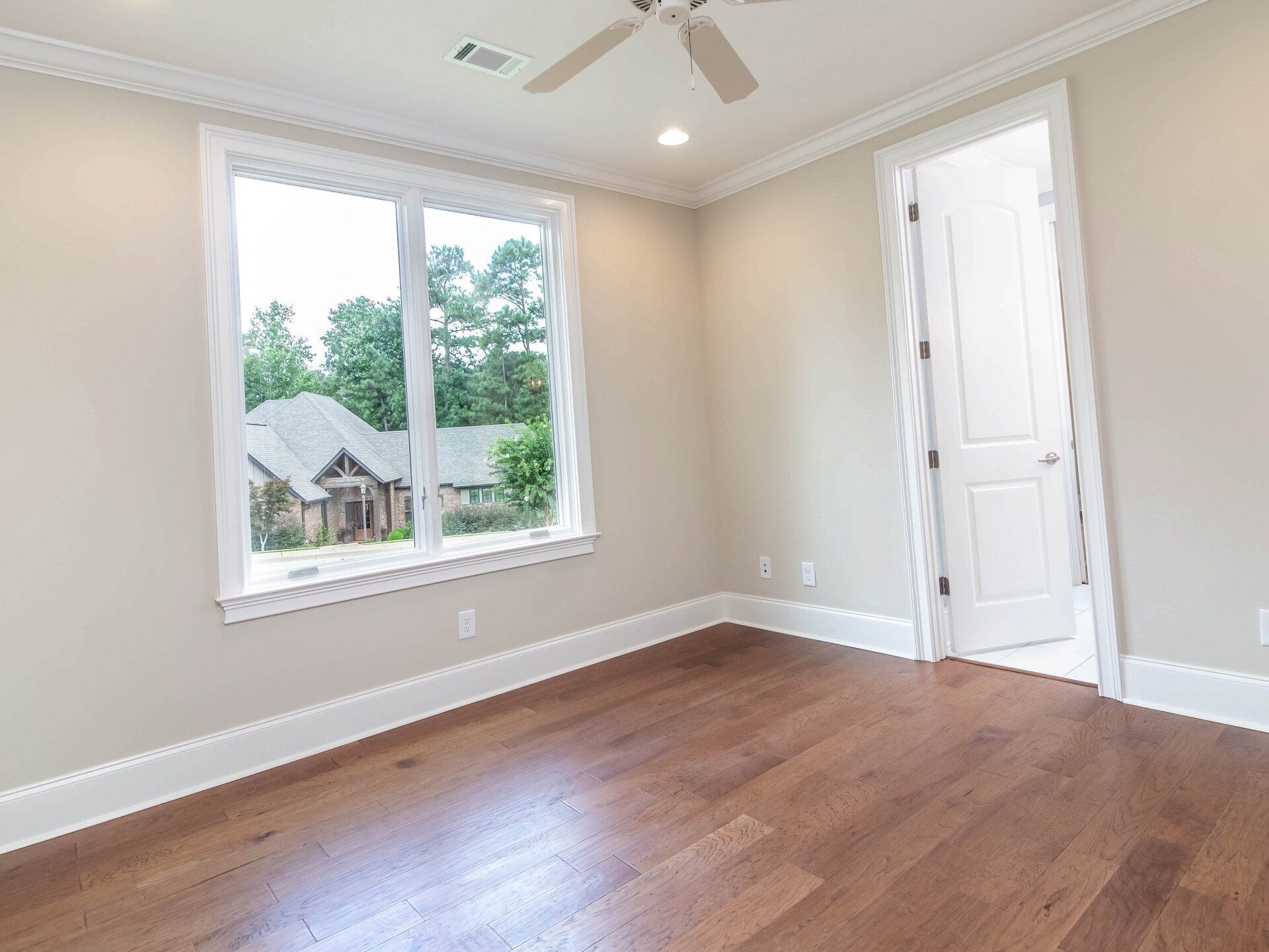 An empty bedroom with hardwood floors and a ceiling fan.