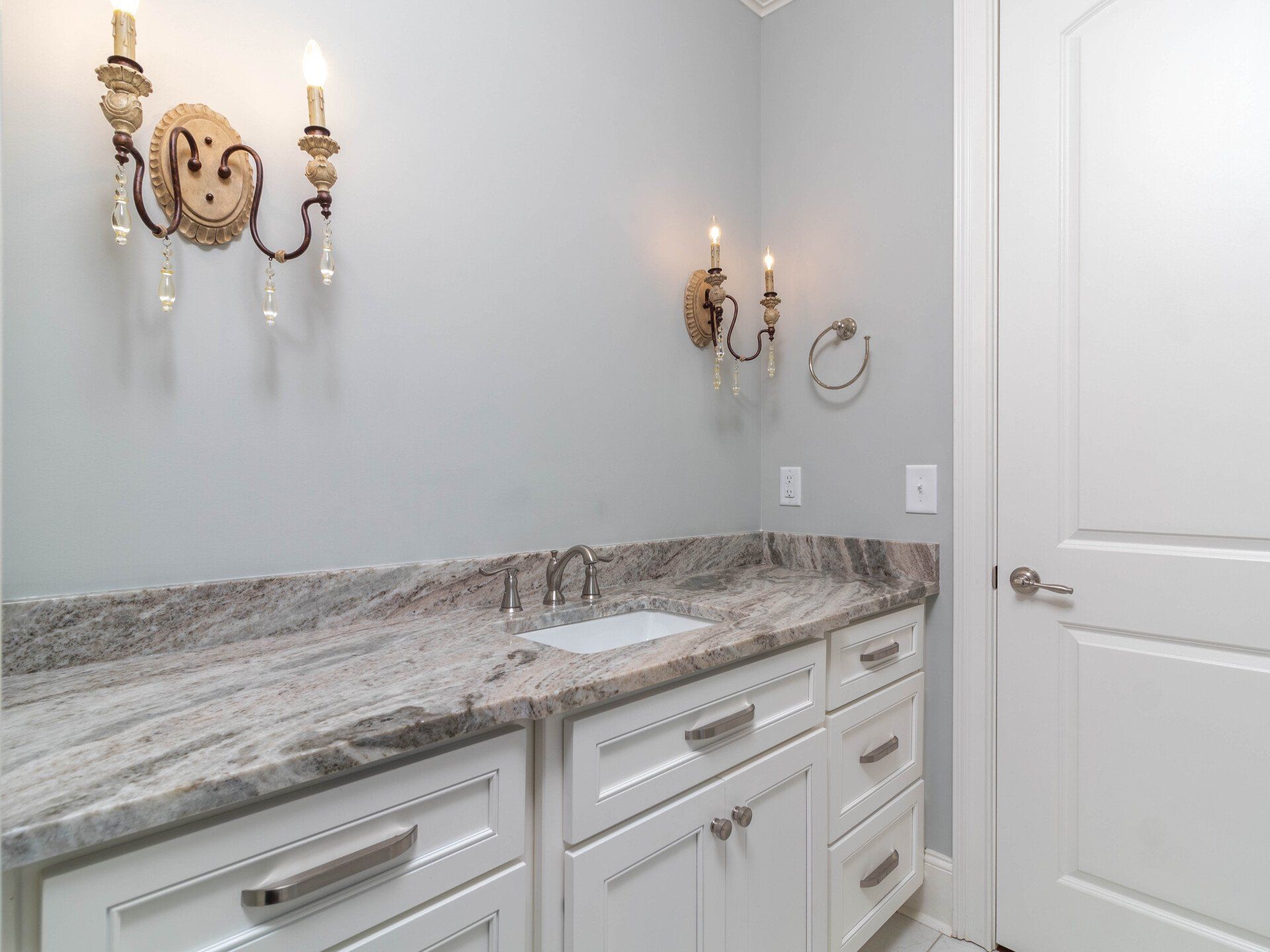 A bathroom with a sink , cabinets , and granite counter tops.