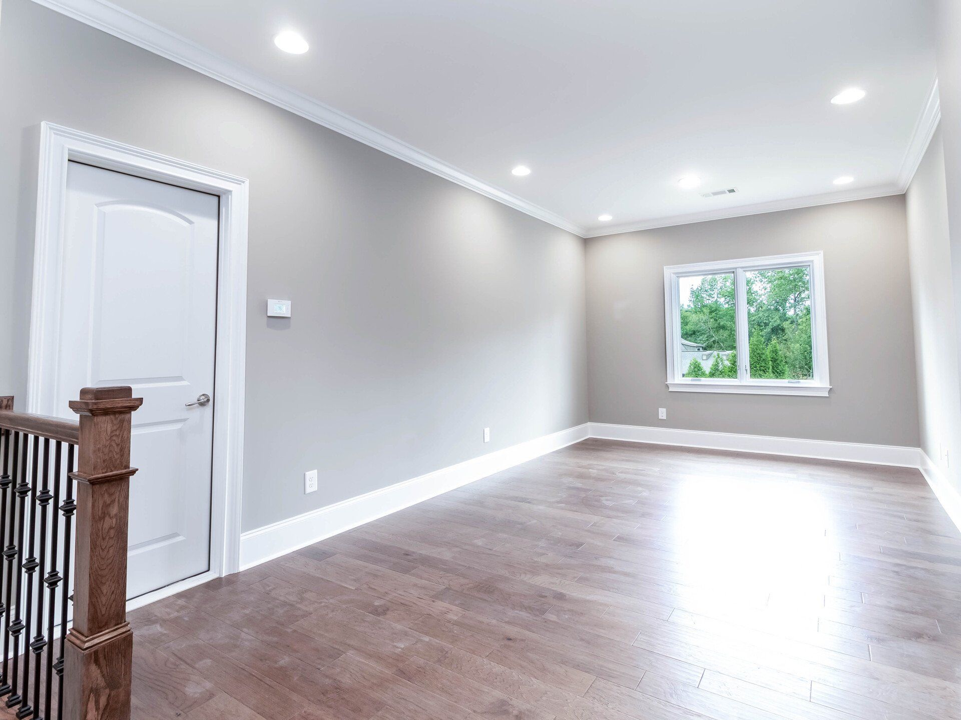 An empty living room with hardwood floors and gray walls.