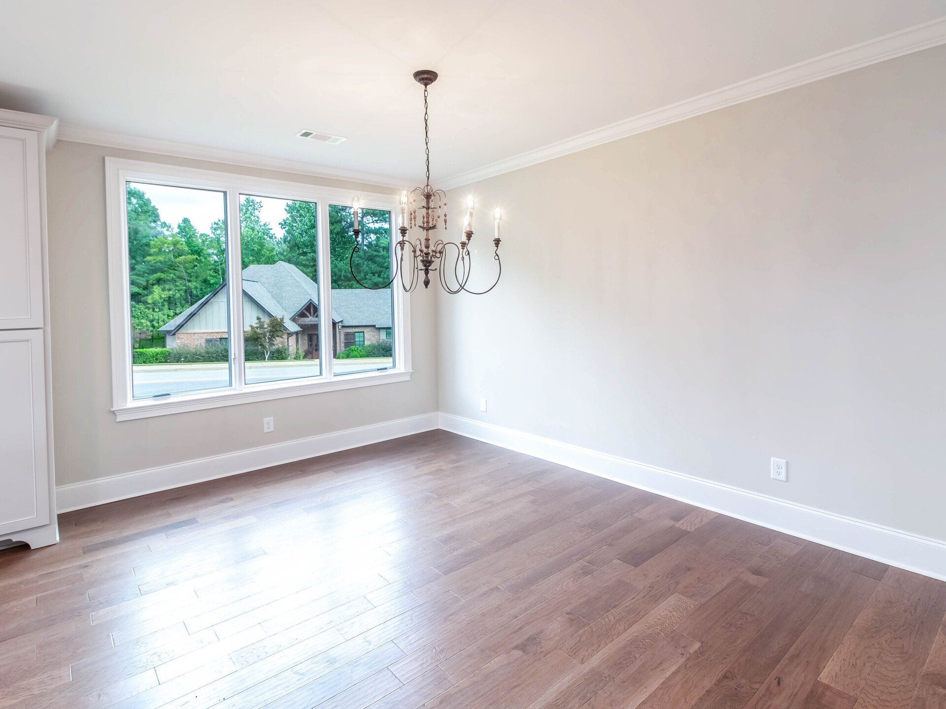 An empty living room with hardwood floors and a chandelier.