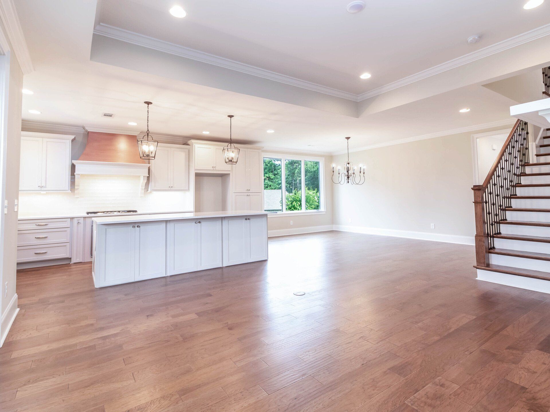 A kitchen with a large island and stairs in a house.