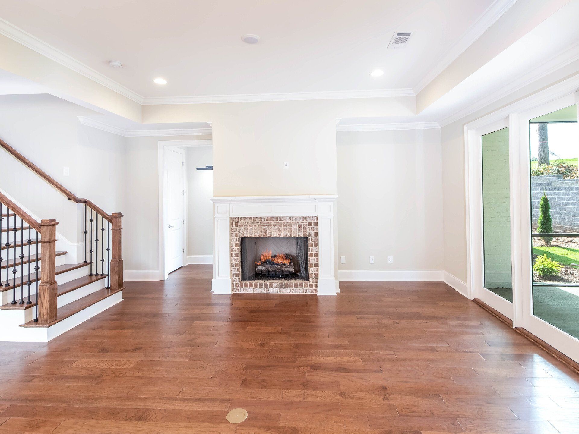 An empty living room with hardwood floors and a fireplace.