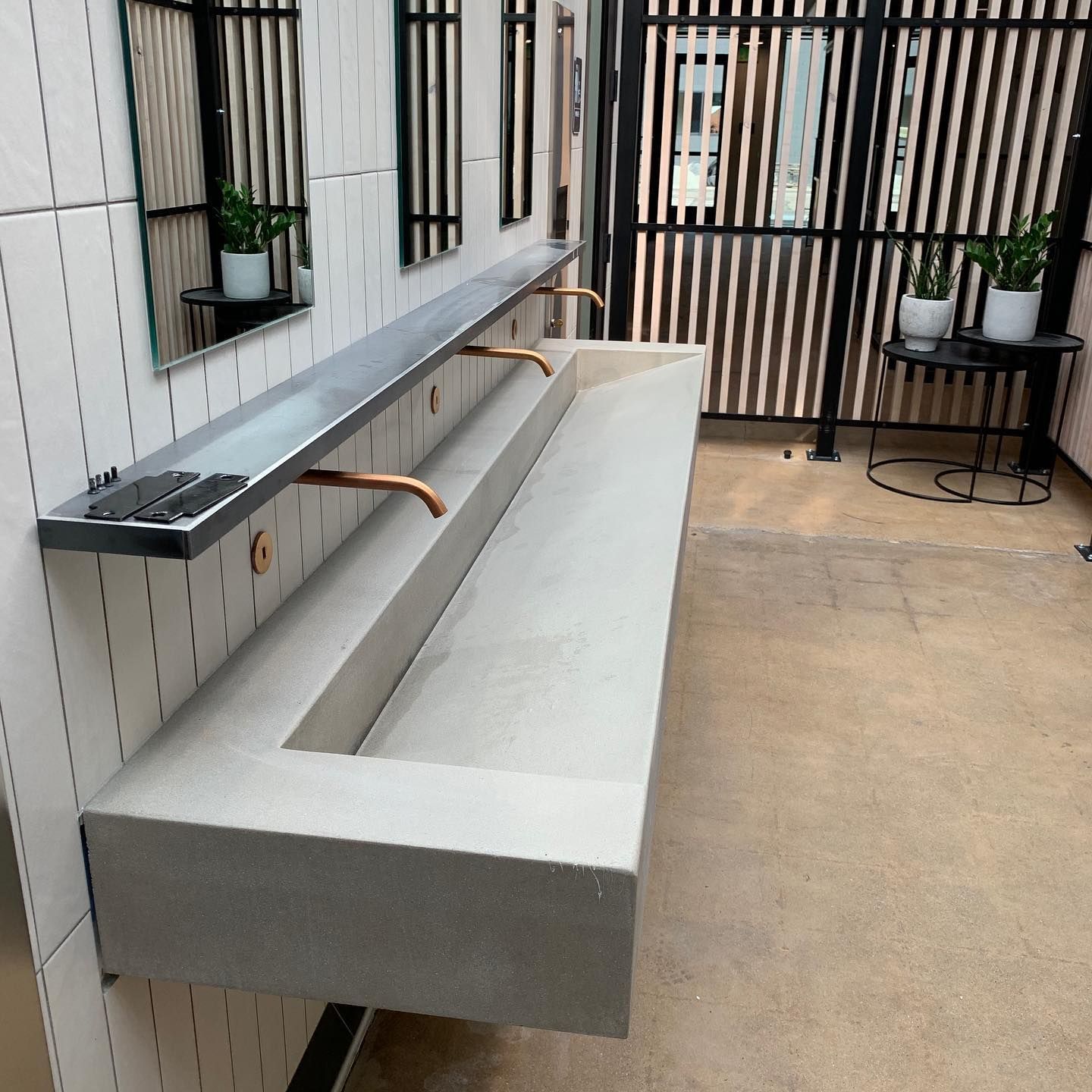 A bathroom with a long sink and mirrors on the wall