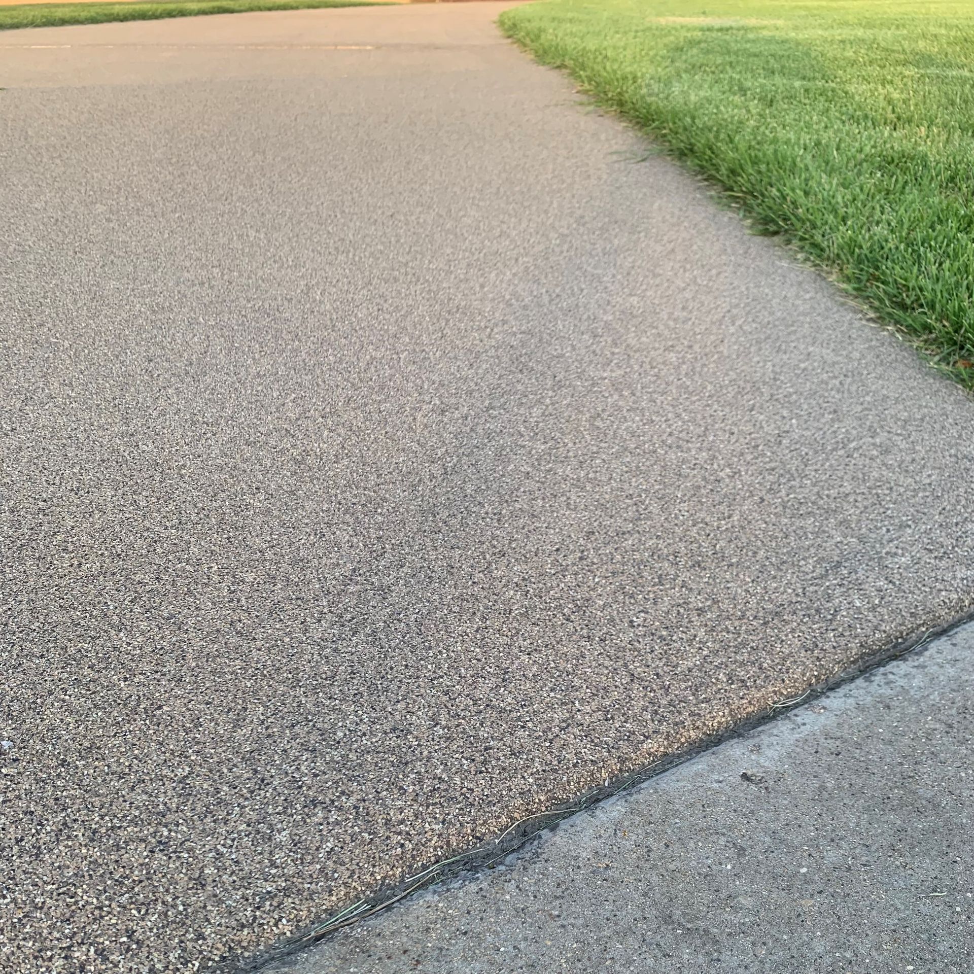 A concrete sidewalk next to a grassy field.