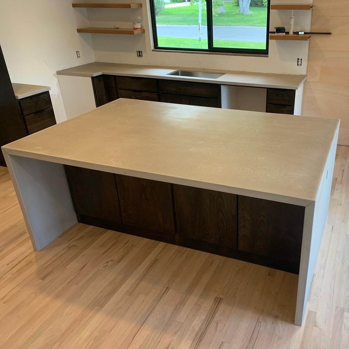 A kitchen with a large concrete counter top and wooden cabinets