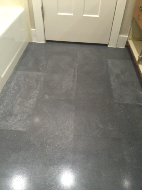 A bathroom with a gray tile floor and a white door